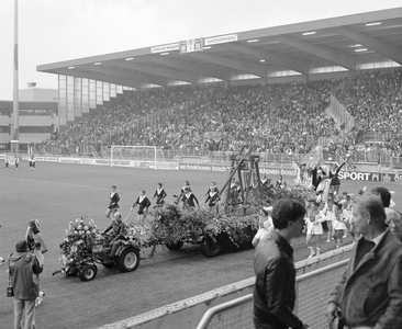885061 Afbeelding van een praalwagen met daarop een houten slinger en 'koning voetbal' zittend op een troon, die langs ...